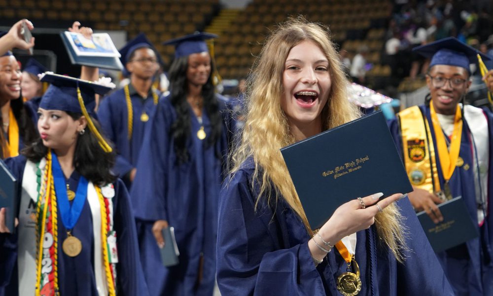 Graduates smiling as they leave the ceremony.