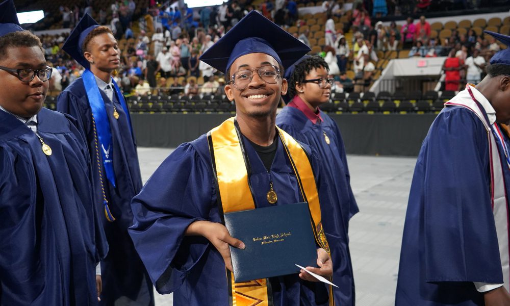 Graduates smiling as they leave the ceremony.