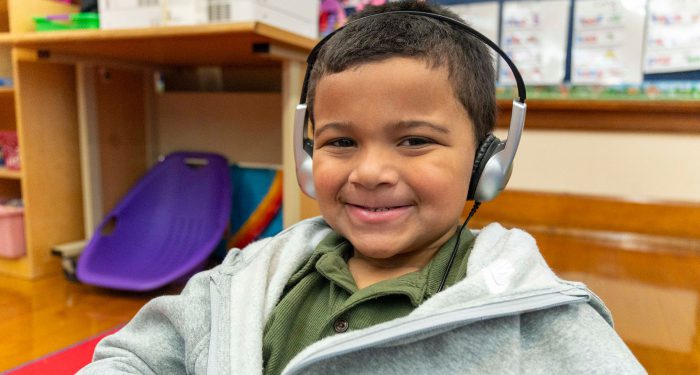 A young child wearing headphones smiling.
