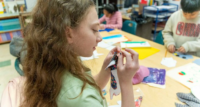 Children in a classroom learning to sew.