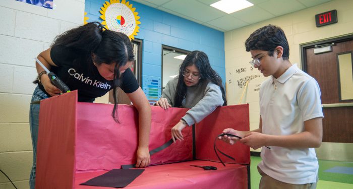 Children glue colorful paper to a bench.