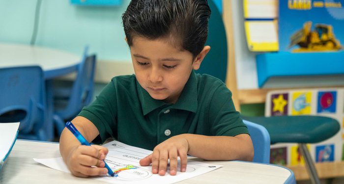 A young child at a table working on an assignment.
