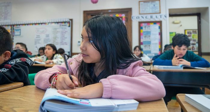 Children at desks writing in workbooks.