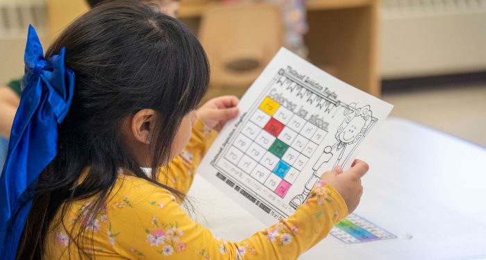A young child looking at a handmade bingo card.