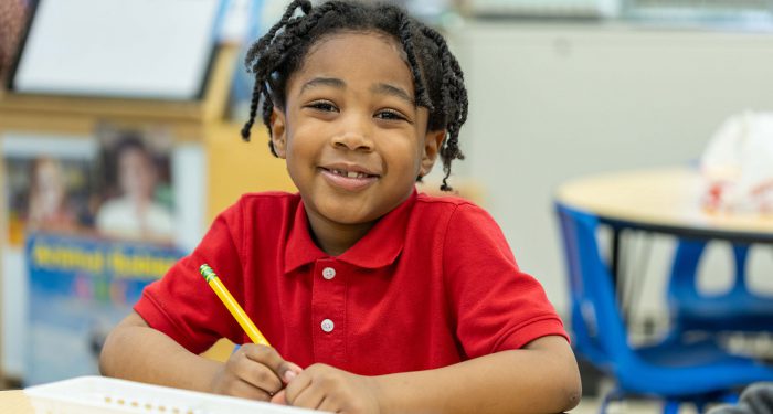 A smiling boy holding a pencil.