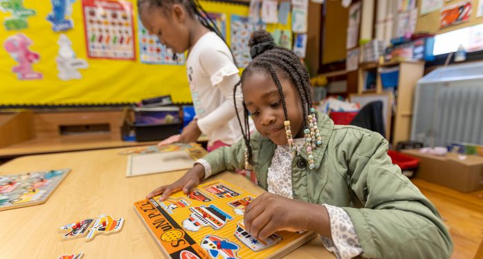 Two young girls putting puzzles together.