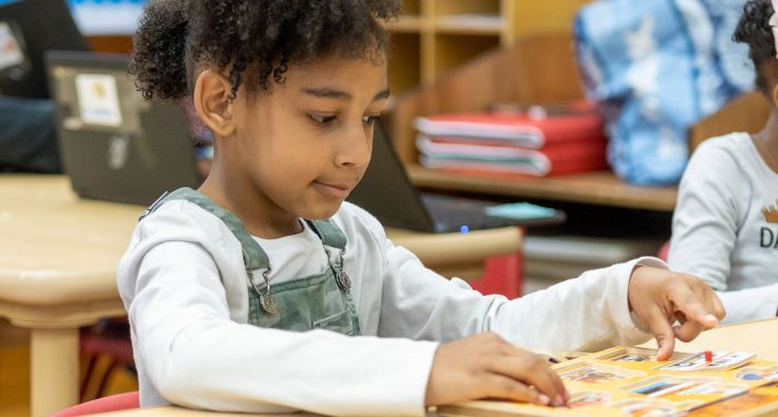 A young girl concentrates as she puts a puzzle together.
