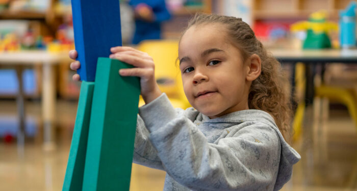 A young girl stacking blocks.