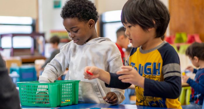 Two young students sort shapes from a basket.