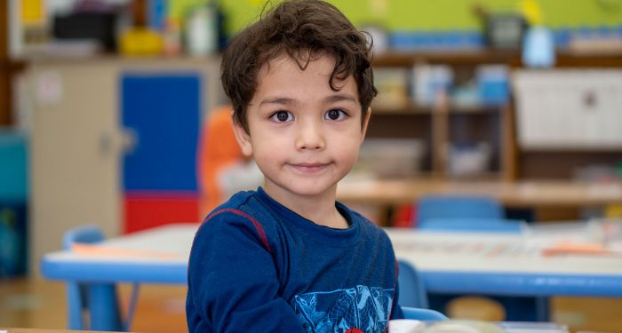 A smiling boy in a classroom.