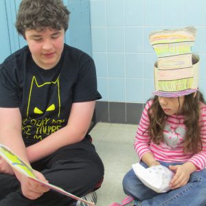An older child reads to a younger child.