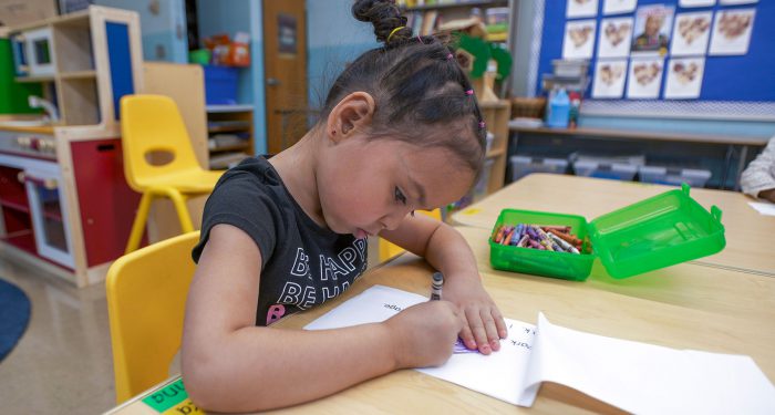 A young girl at a table coloring.