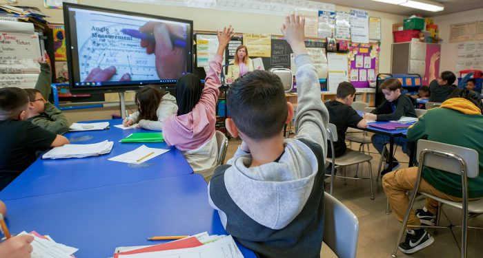 Students raise their hands in a classroom.