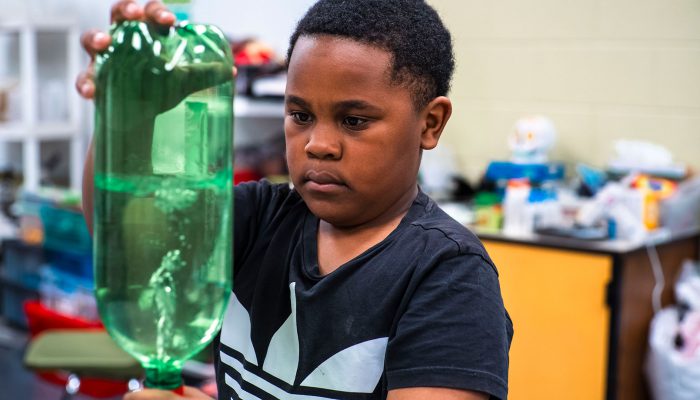 A student replicates a tornado using soda bottles filled with water.