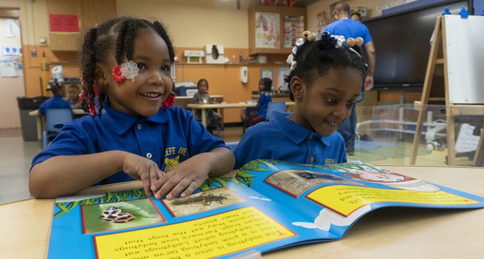 Two young girls look at a picture book