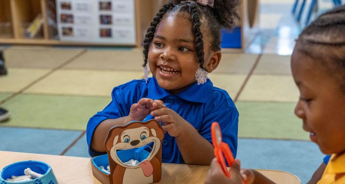 Little girls playing at a table.