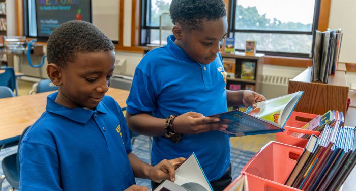 Two students in a library looking at books.