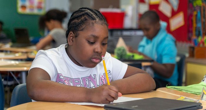 A student sitting at a table writing.