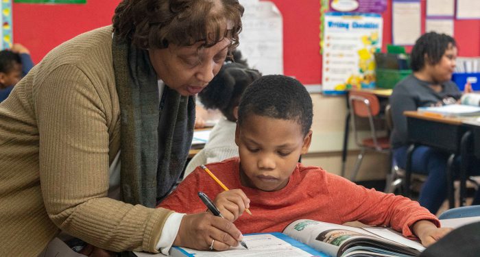 A teacher helps her young student.