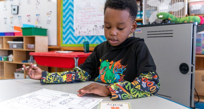 A young child in a classroom practices writing.