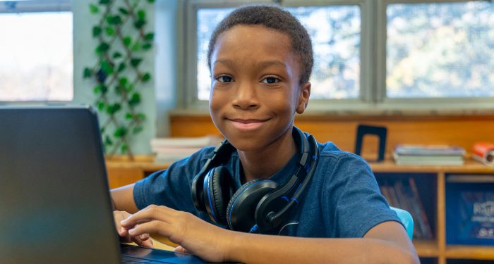 A child in a classroom smiling.