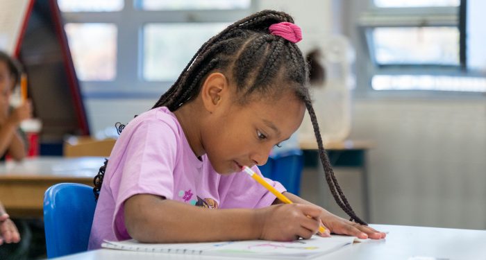 A young girl writing in a workbook.