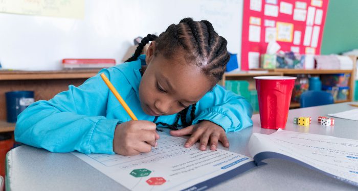 A student in a classroom writing on a worksheet.