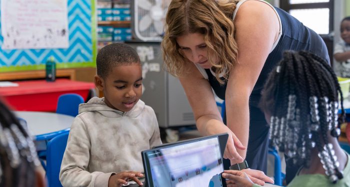A teacher helps students use computers.