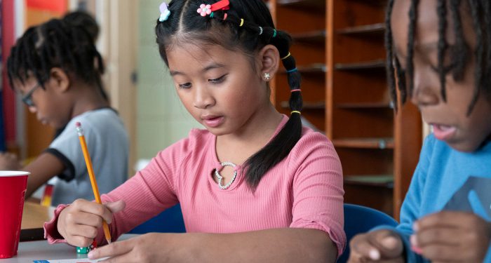 Students in a classroom work on an assignment.