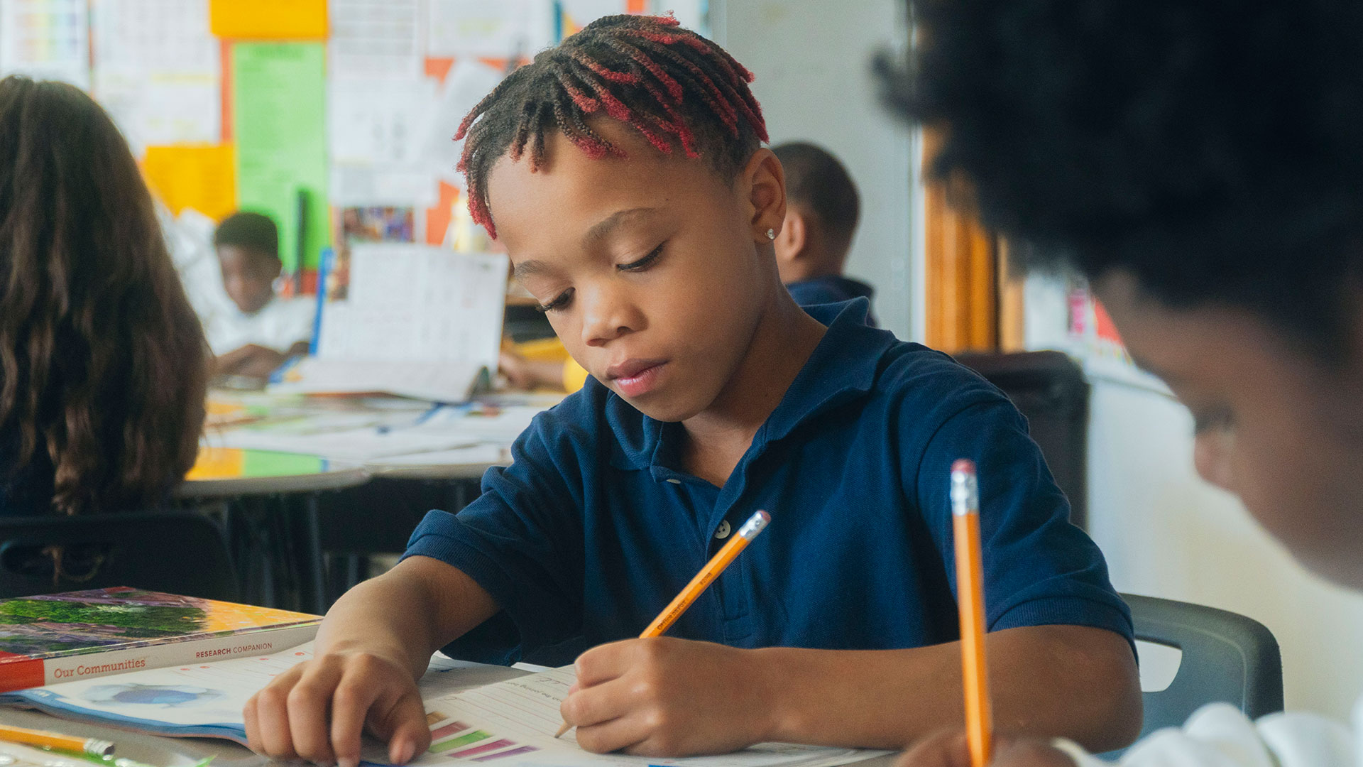 Students in a classroom writing in workbooks.