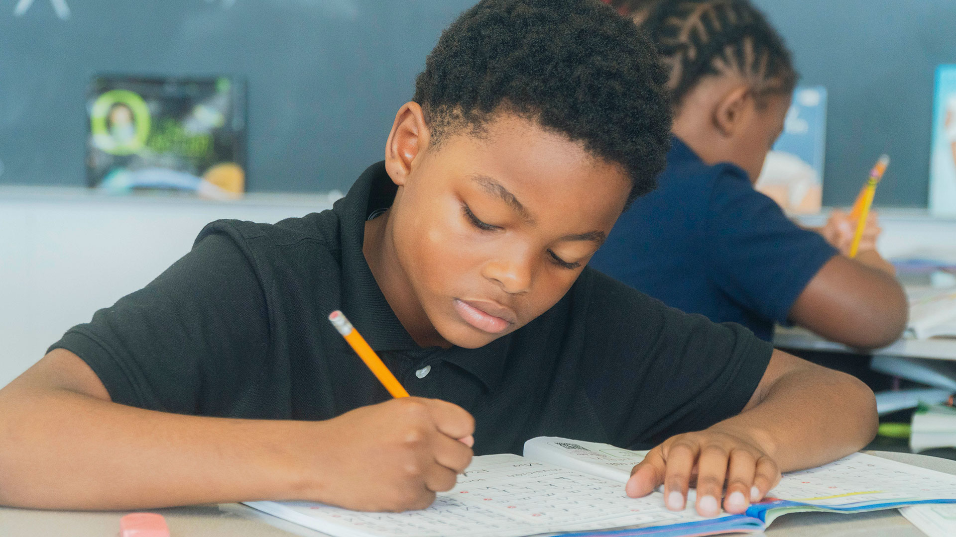 Students in a classroom writing in workbooks.