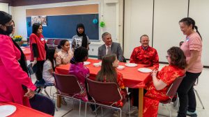 Students and staff wait at a table for food.