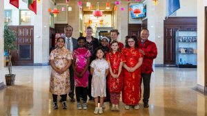 Children in traditional Chinese clothing with school leaders.