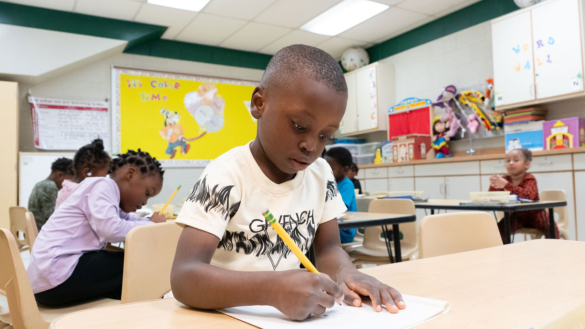 Young children in a classroom work on an assignment.