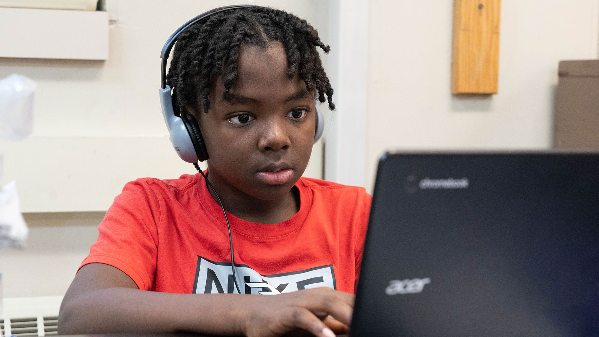 A boy with headphones using a computer.