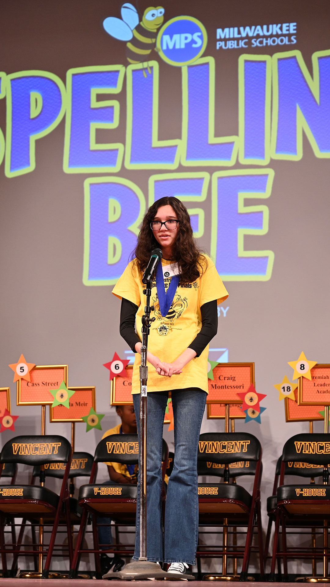 Ellen spelling out a word at the microphone.