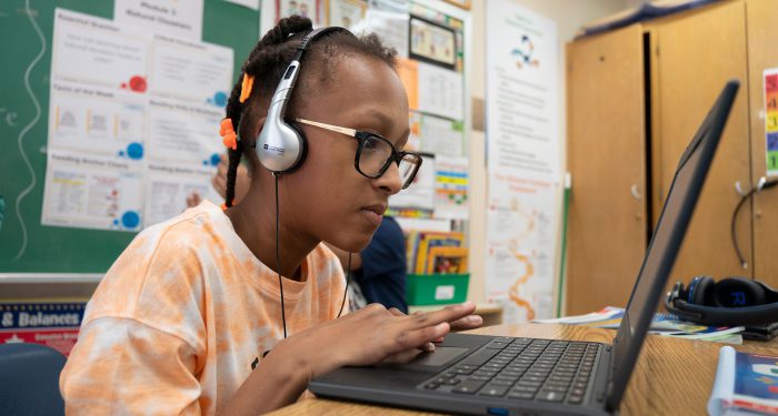 A child with headphones uses a computer.