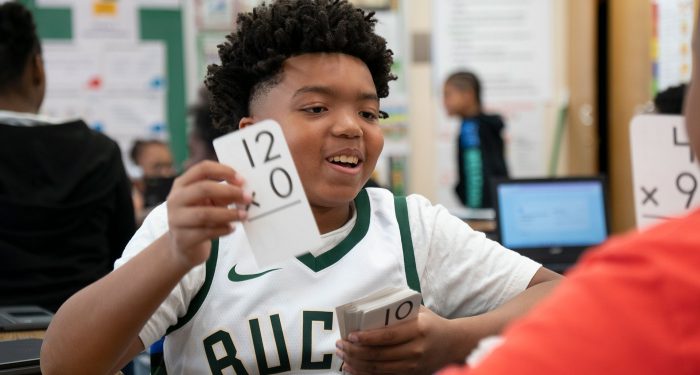 Students in a classroom quizzing each other with flashcards.