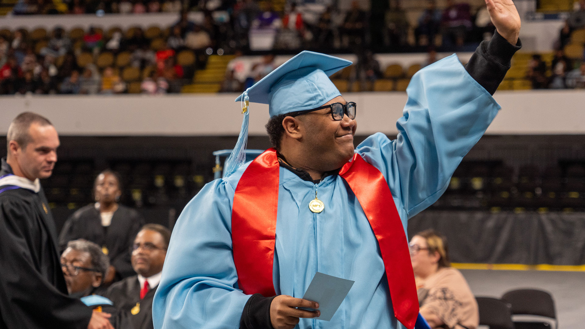 A graduate waves to the crowd.
