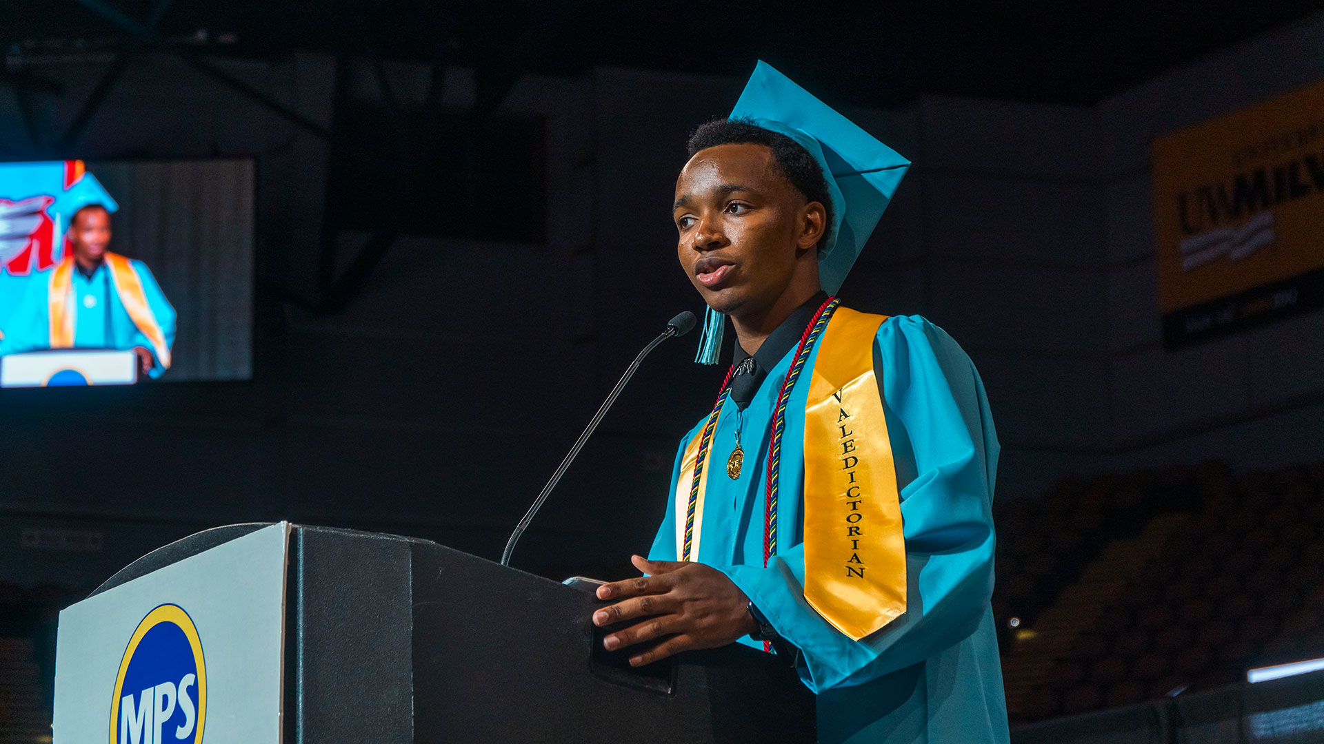 A graduate speaking at the podium.