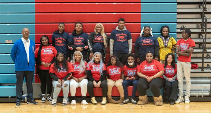A group of students in matching shirts with school leadership.