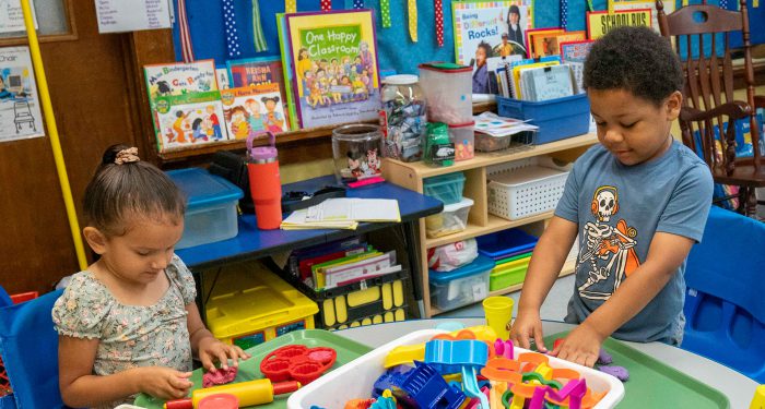 Young children in a classroom playing with PlayDoh.