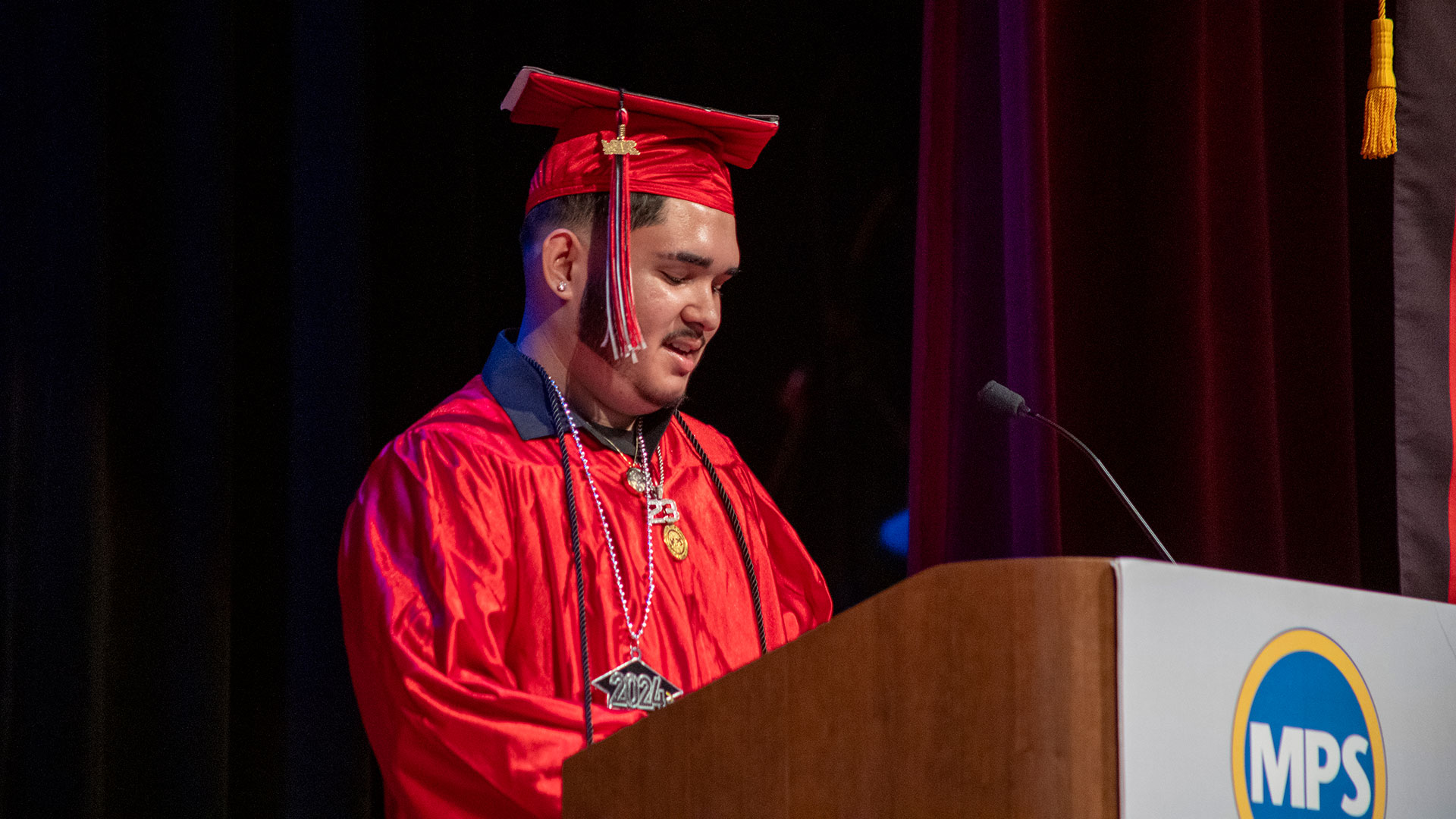 A graduate in a cap and gown at a podium.