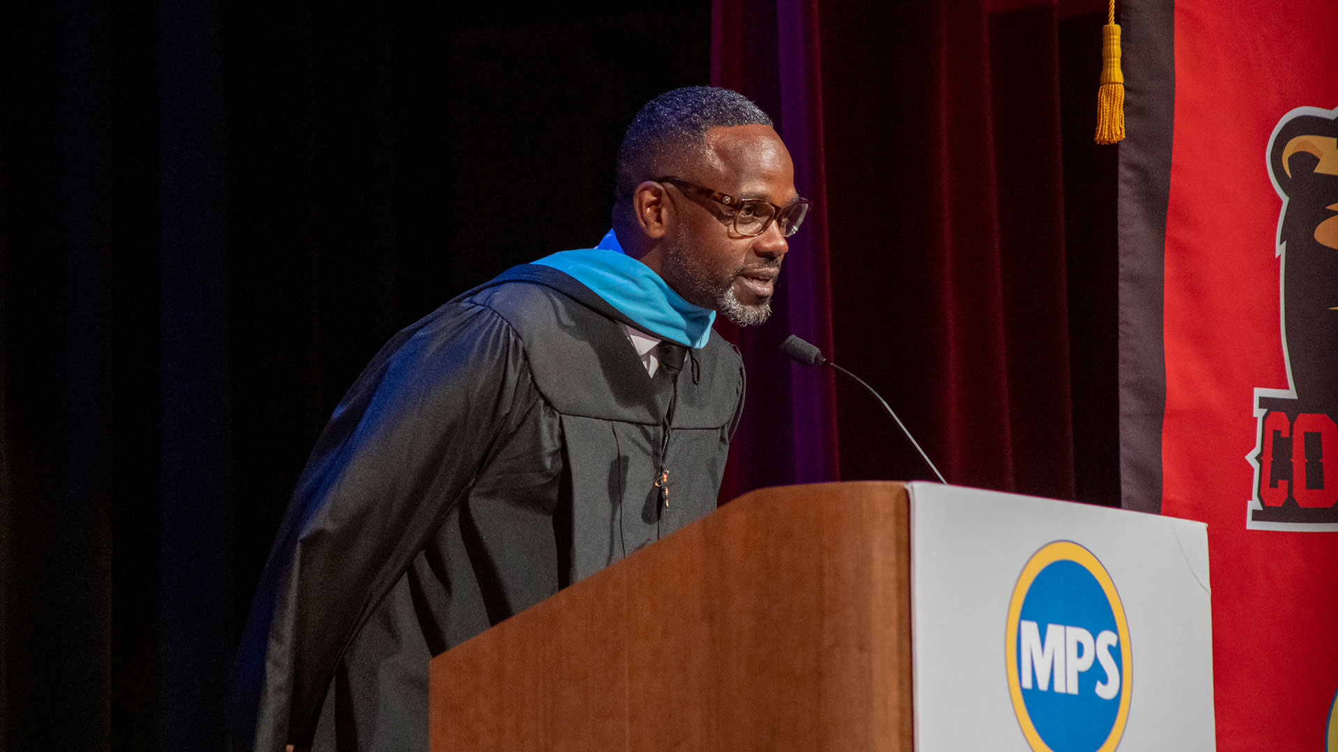 Principal Brazil in a graduation gown at a podium.