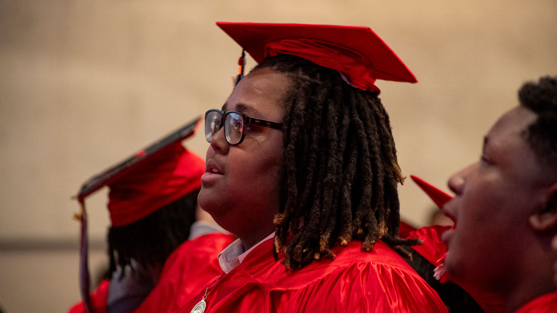 A graduate in a red cap and gown.