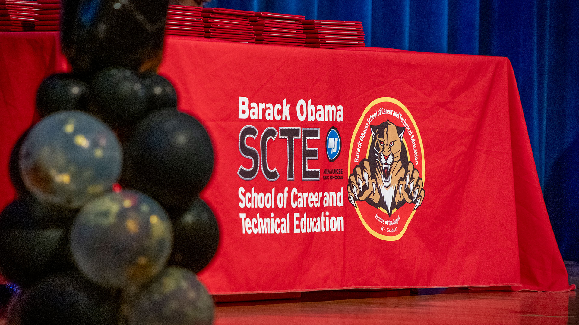 Diplomas on a table draped in an Obama School table cloth.