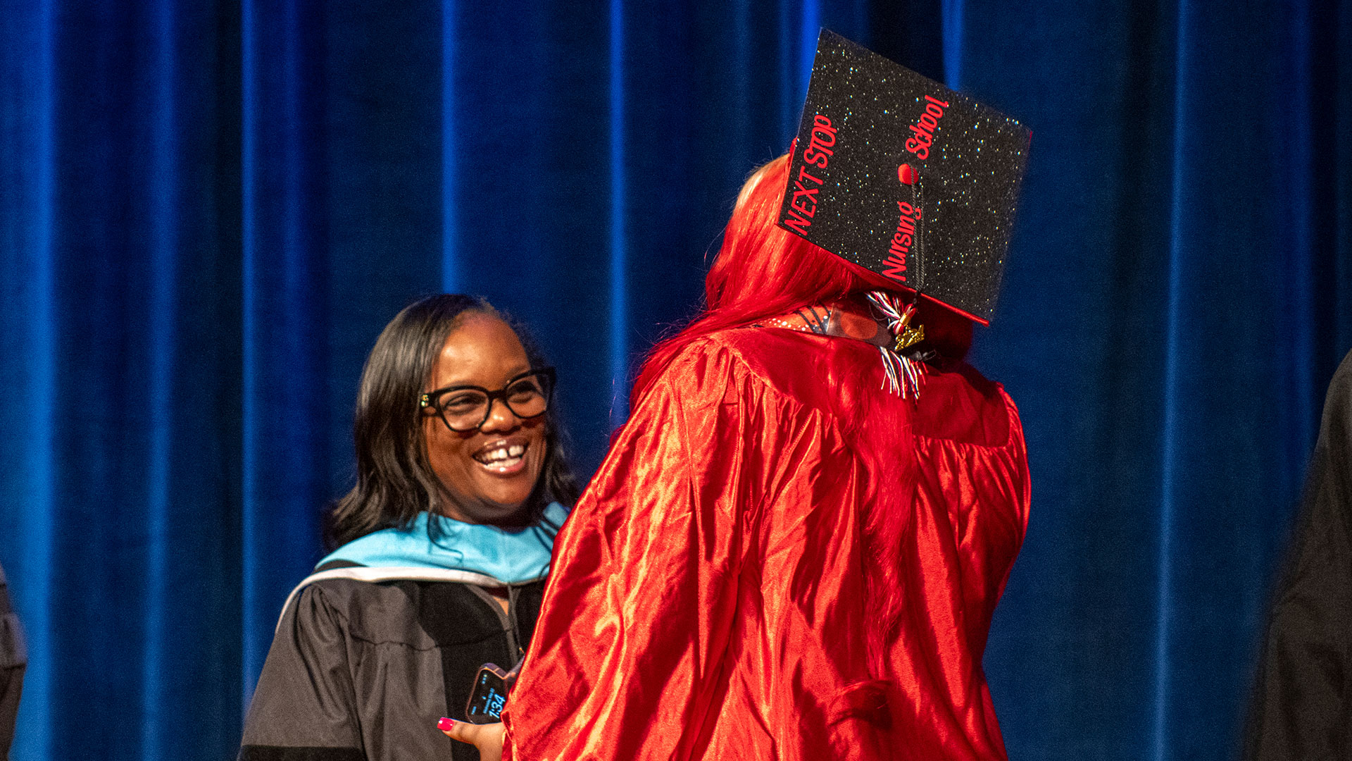A graduate with "Next stop nursing school" on her cap, accepts her diploma.