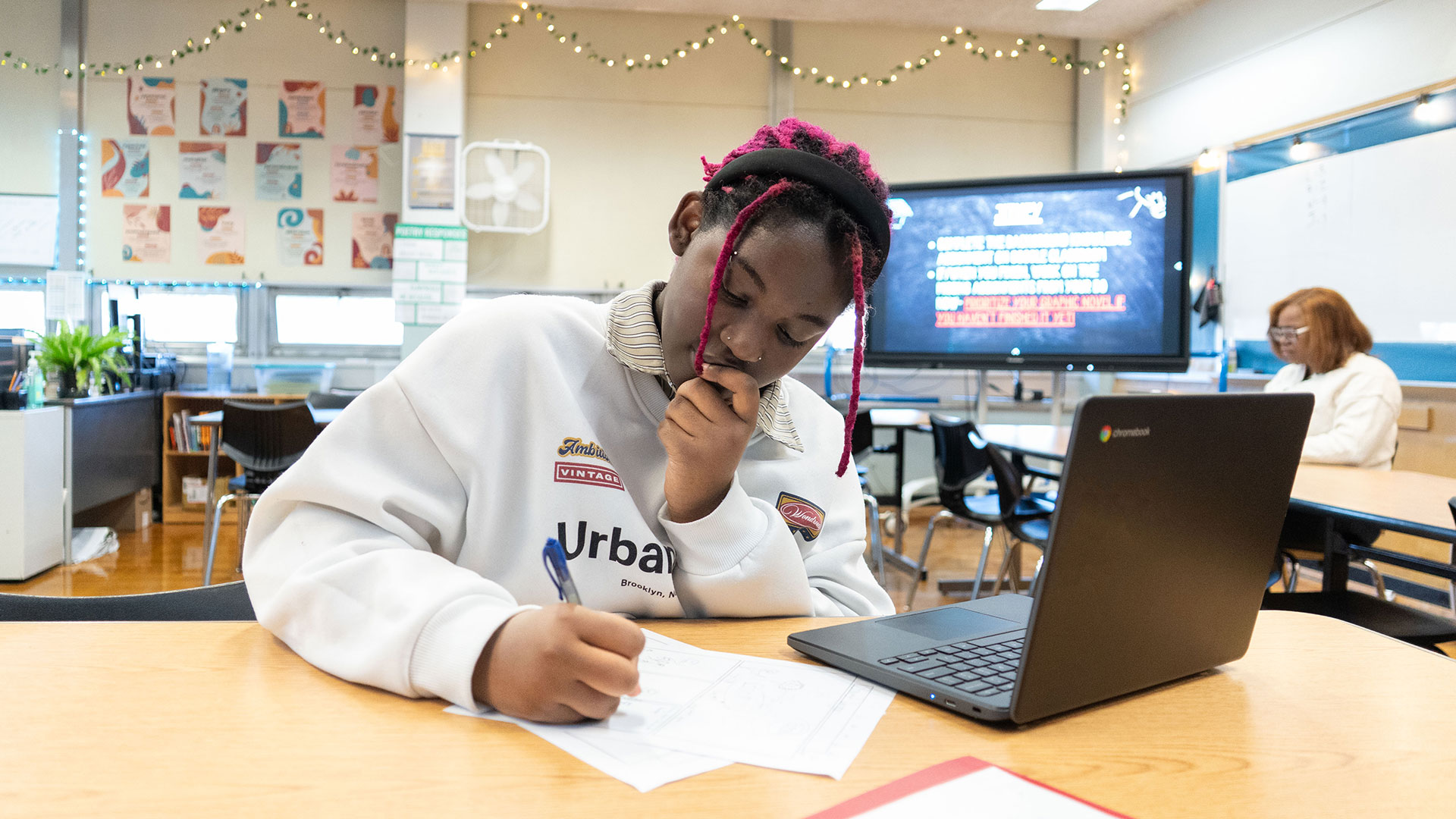 A girl in a classroom taking notes.