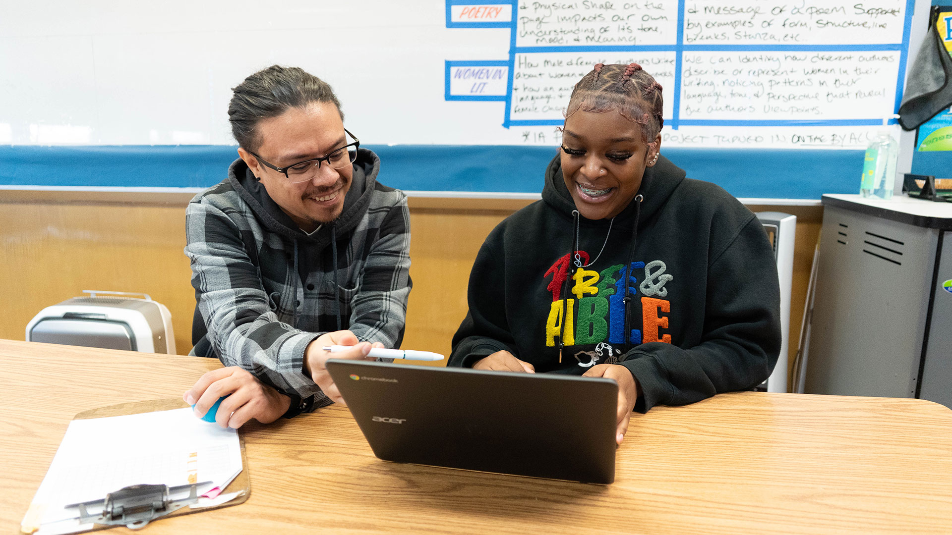 A student and teacher working on a computer.