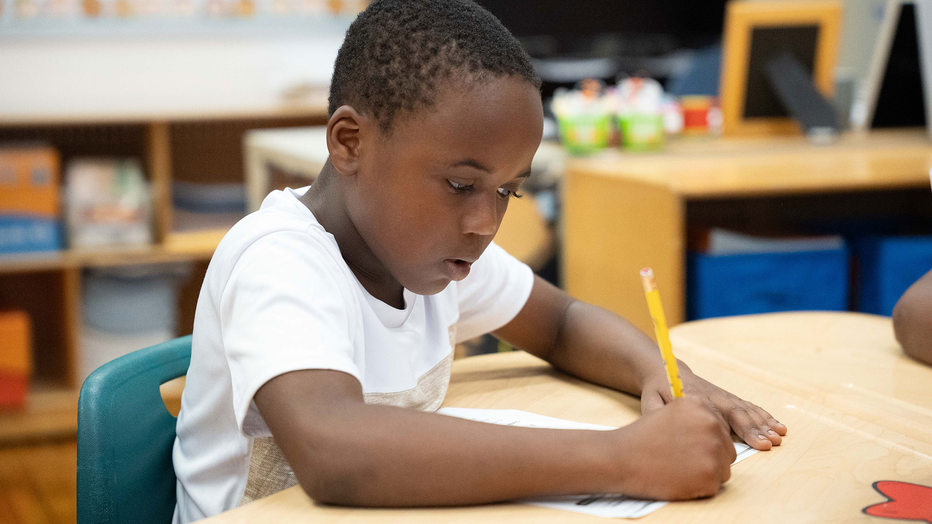 A young child in a classroom working on an assignment.